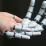 Close-up robotic hand touching human skin.